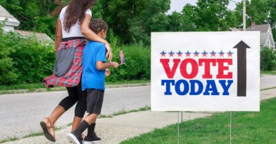 siblings walking down sidewalk towards polling place