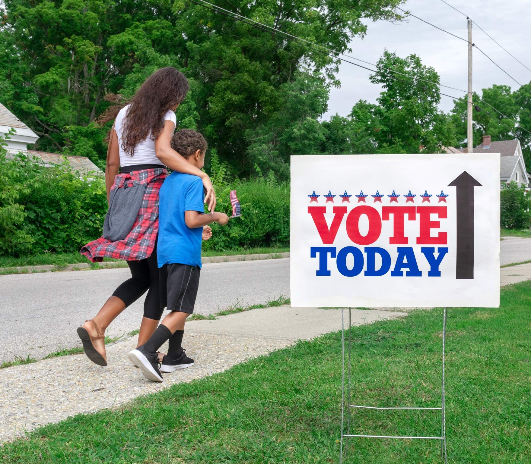 siblings walking down sidewalk towards polling place