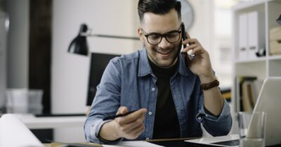 Person on the phone making political fundraising calls with a computer and call sheets in front of them a desk.