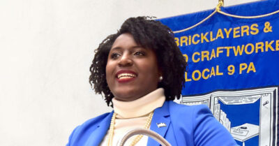 Speaker of the House Rep. Joanna McClinton speaking behind a podium wearing a blue blazer
