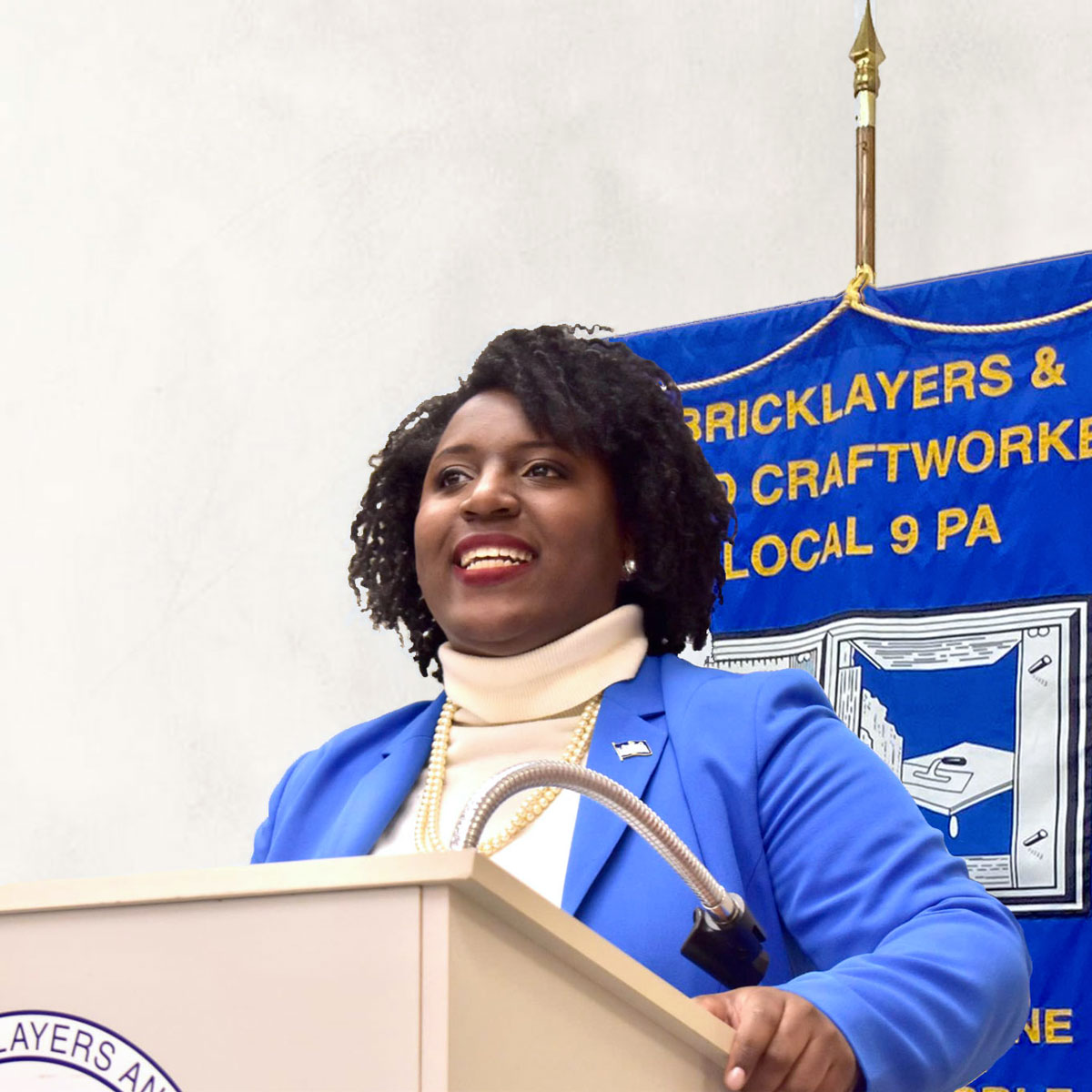 Speaker of the House Rep. Joanna McClinton speaking behind a podium wearing a blue blazer