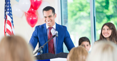 Political candidate in a suit and tie with family at a campaign launch