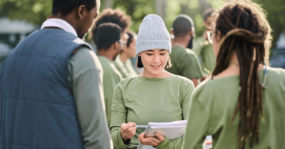 A field organizer looking at a notebook with a volunteer recruitment plan and speaking with prospective volunteers.