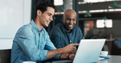 Two people sitting in an office reviewing donations pages for political campaigns on a computer.