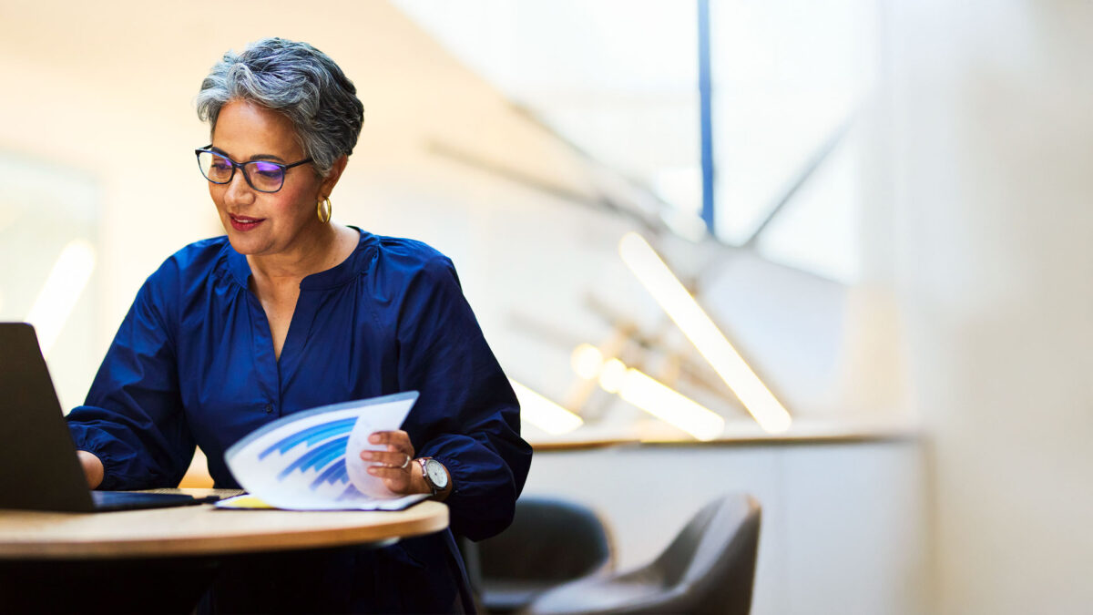 Woman reviewing printed reports at a laptop, representing campaign finance work.