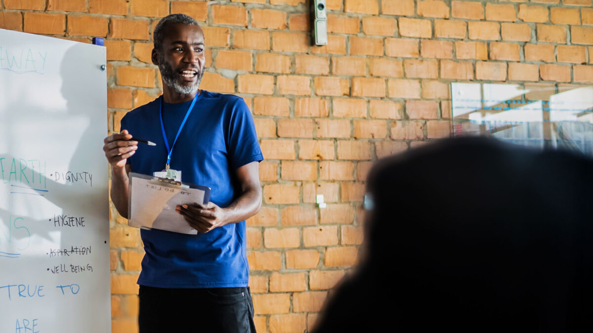 Man speaking at a whiteboard session, representing campaign training or organizing strategy.