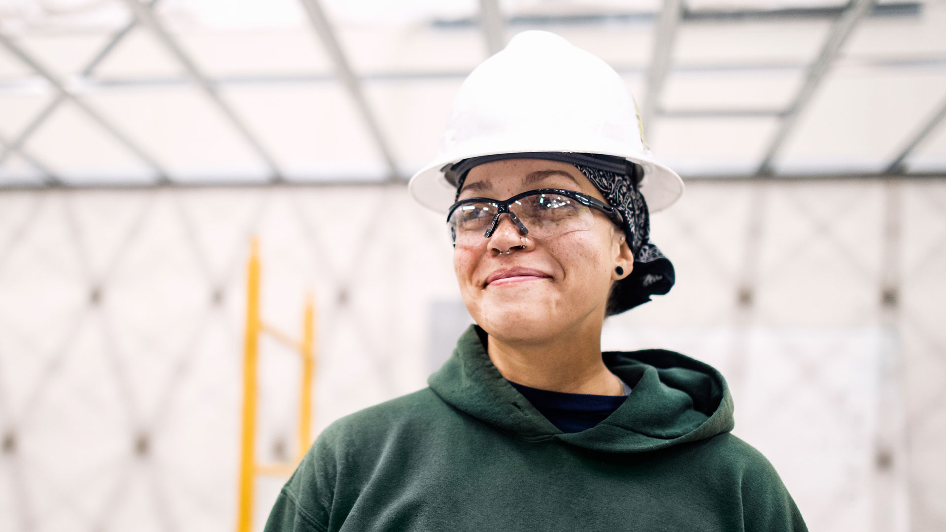Smiling worker wearing a hard hat and safety glasses, representing union labor and strong workplace protections.