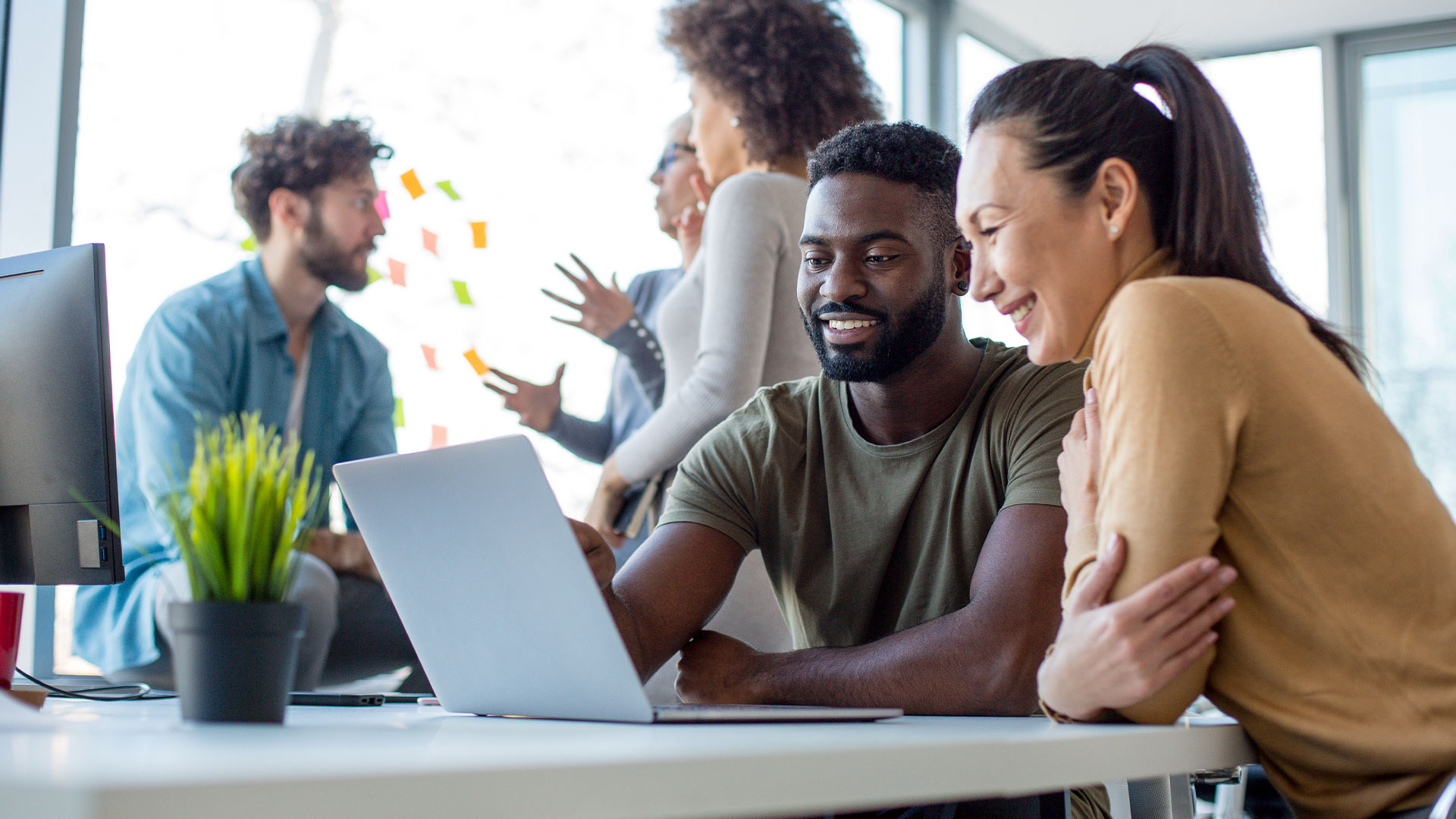 Two campaign staff reviewing fundraising and compliance data on a laptop.