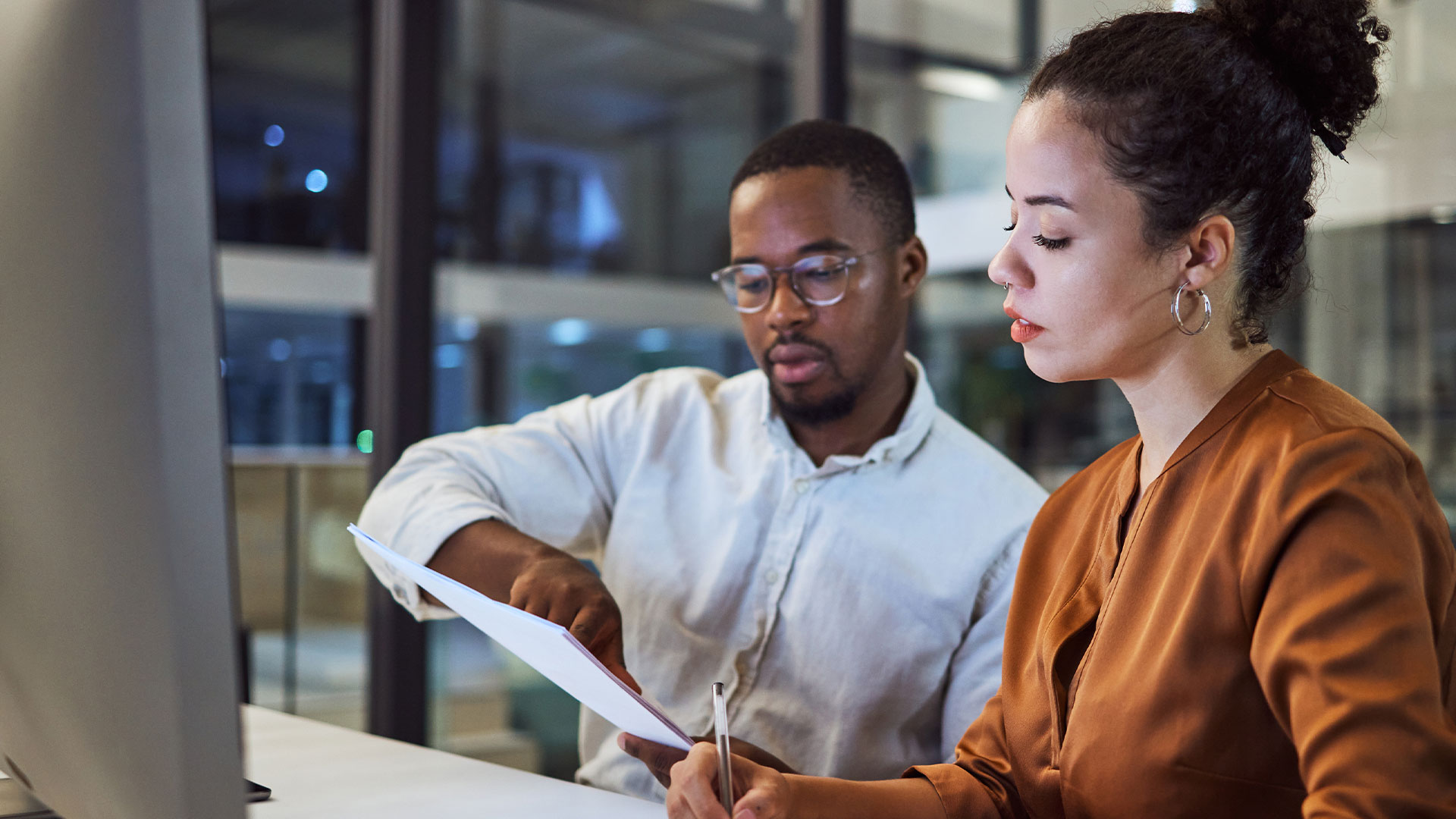 Two team members reviewing printed compliance and finance records.