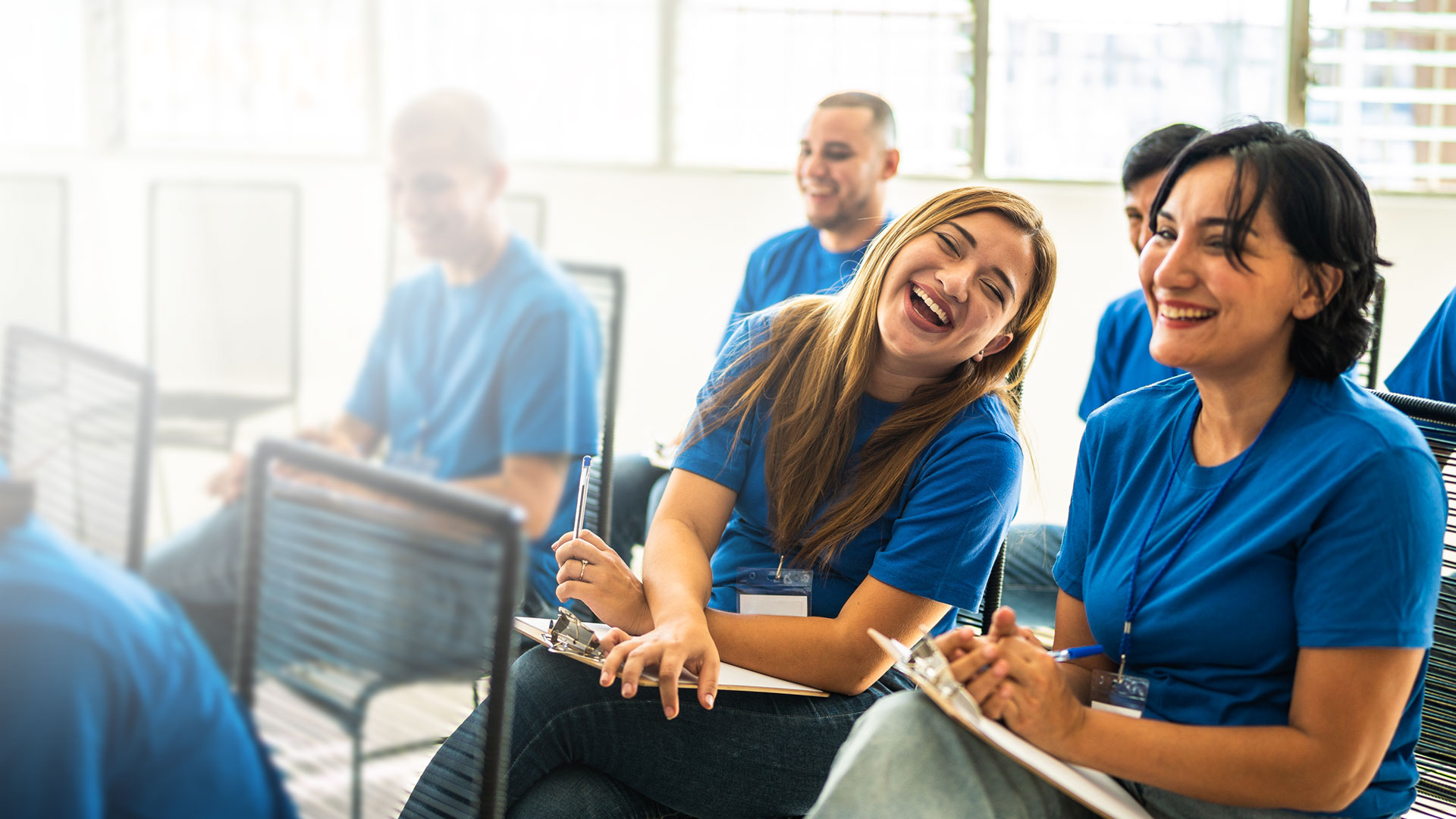 Two volunteers seated together, laughing while reviewing campaign work on a table.