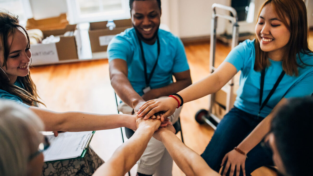 Group of volunteers in a circle with hands stacked in the center before an organizing shift