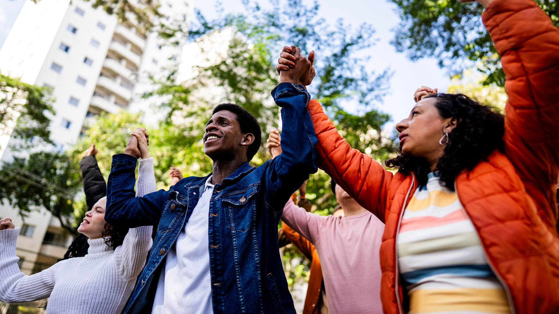 Advocates standing outdoors with hands raised together during a rally