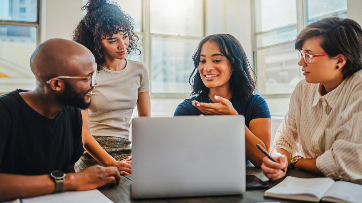 A group of colleagues collaborating around a laptop, representing how ActionKit helps teams work together seamlessly.