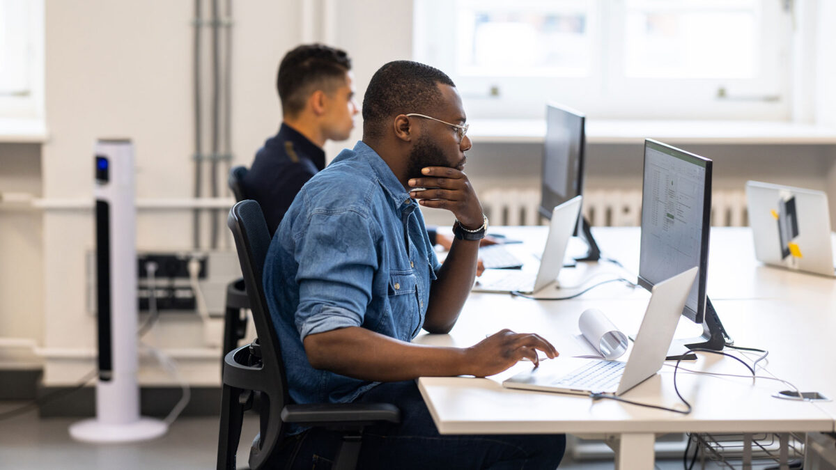 Two people sit on computers at an office looking at the voter file