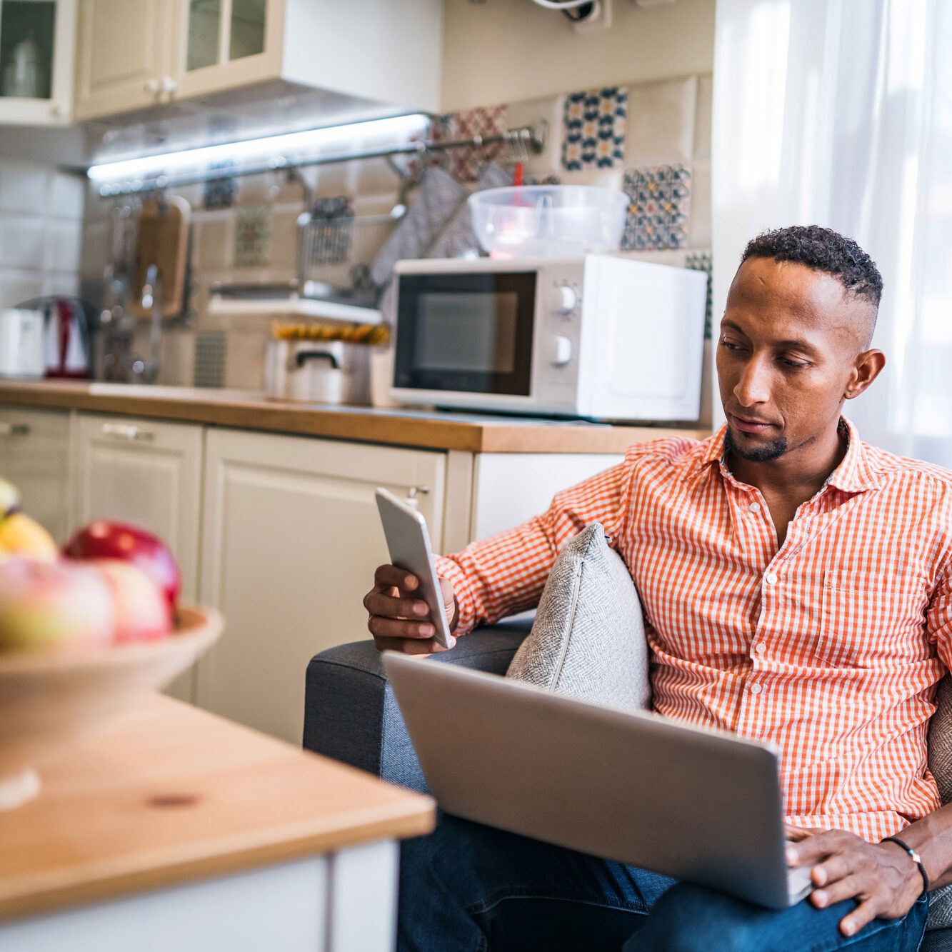 man checking his phone while on his laptop