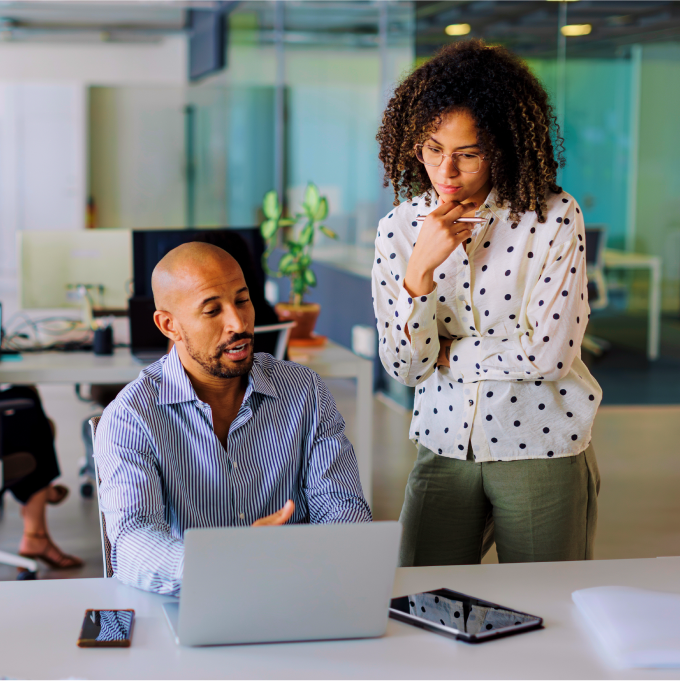 Two colleagues collaborating at a laptop in a modern office.