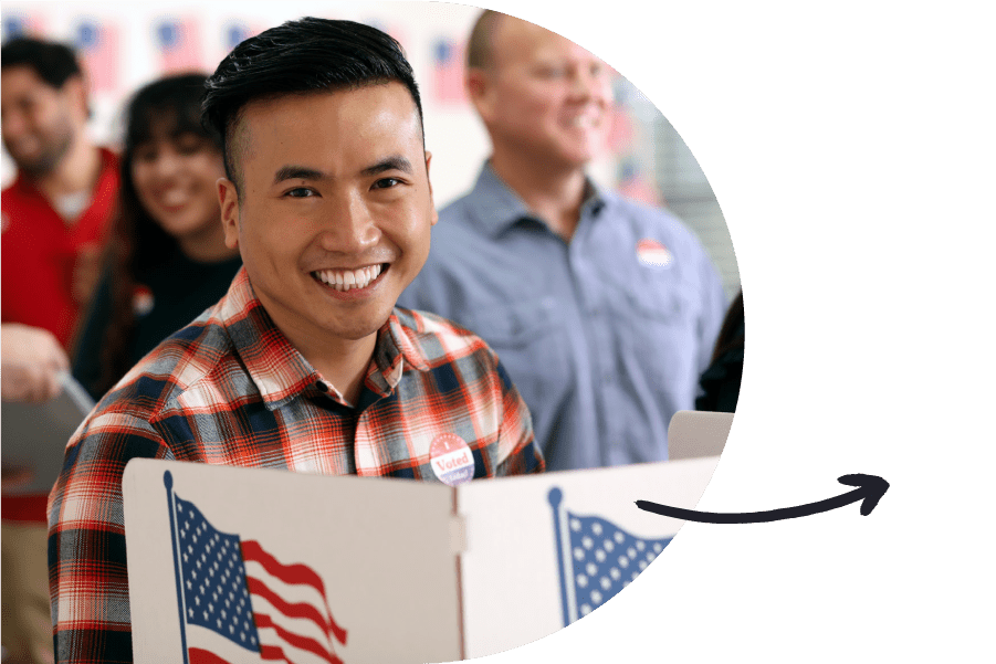 A person smiling at a voting booth with a line of voters behind them